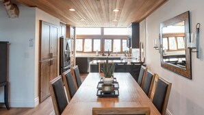 A spacious dining area with a long wooden table, surrounded by chairs, and a patterned rug. - Stunning Eastern Sierra Retreat: 3 Bed+Loft/3 Baths, Spacious, Pet-Friendly (Mammoth Lakes)