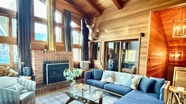 A spacious living room with a fireplace, a ceiling fan, and large windows. - Stunning Eastern Sierra Retreat: 3 Bed+Loft/3 Baths, Spacious, Pet-Friendly (Mammoth Lakes)