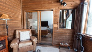 A cozy room with a leather sofa, a treadmill, and a large sliding glass door leading to a dining area. - Stunning Eastern Sierra Retreat: 3 Bed+Loft/3 Baths, Spacious, Pet-Friendly (Mammoth Lakes)