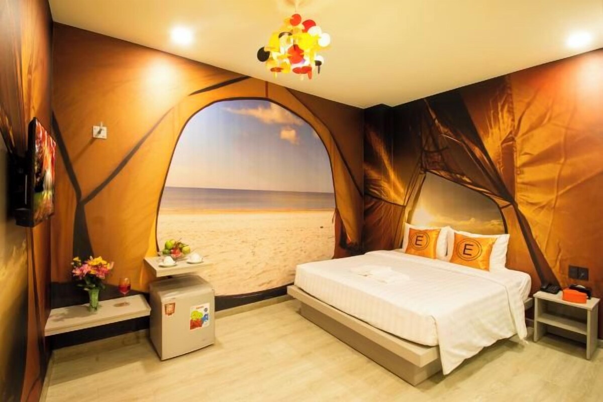 Un dormitorio con cama, mesitas de noche, un escritorio pequeño y vistas a la playa.