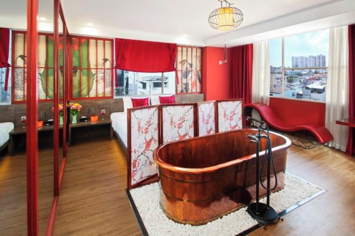 A modern room with a large bathtub, a red chair, and a view of the city.