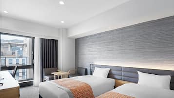 A hotel room with two beds, a desk, a chair, and a view of the cityscape.