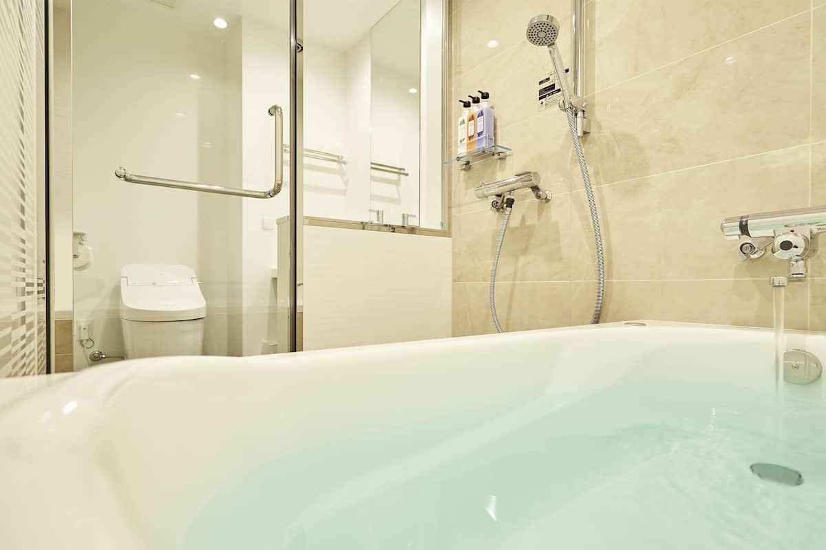 Une salle de bain moderne avec une baignoire, une cabine de douche en verre et des barres d’appui.