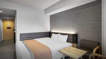 Habitación de hotel con una cama grande, una mesita de noche, una silla y una pared con textura.