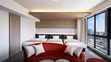 Ett modernt hotellrum med en stor säng, en röd soffa och utsikt över staden.