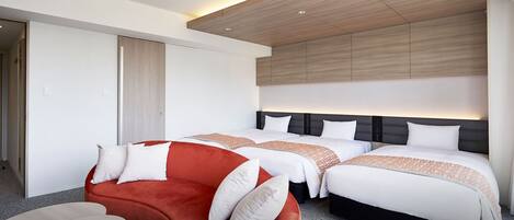 A modern hotel room with two beds, a red sofa, a small table, and a wooden ceiling.