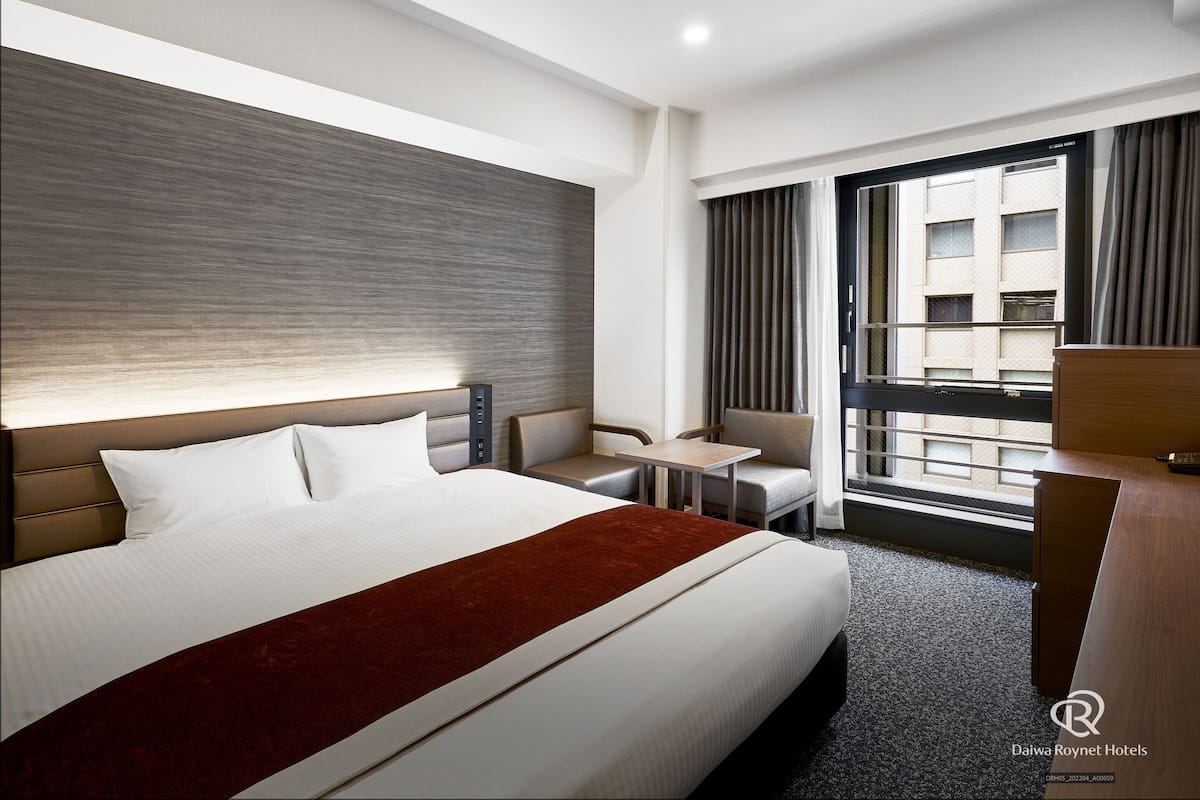Une chambre d’hôtel avec un grand lit, un bureau, une chaise et une vue sur la ville.