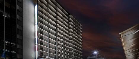 A high-rise hotel with multiple balconies, a modern architectural design, and a well-lit facade.