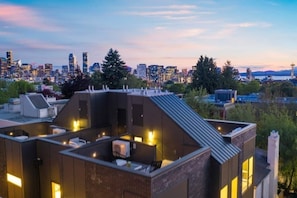 A modern building with a rooftop terrace featuring outdoor seating and a city skyline view in the background. - ⚡️The Brooklyn⚡️CENTRAL Capital Hill with Perfect Walking score🚶🏻‍♂️with Rooftop views (Seattle)