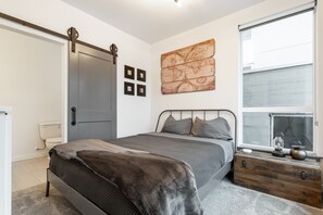 A bedroom with a bed, a dresser, a window with a view, a door, and a wall with a world map artwork. - ⚡️The Brooklyn⚡️CENTRAL Capital Hill with Perfect Walking score🚶🏻‍♂️with Rooftop views (Seattle)
