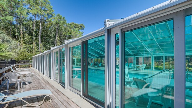Una terrazza con pareti di vetro, sedute all'aperto e zona piscina.