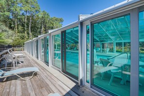 A deck with glass walls, outdoor seating, and a pool area. - Walk to Myrtle Beach: Condo w/ Resort Perks (Myrtle Beach)
