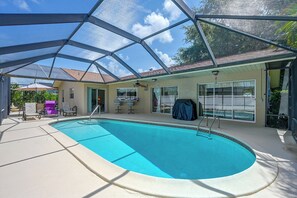 Ein überdachter Pool mit Dachkonstruktion, Stühlen und einem Tisch.