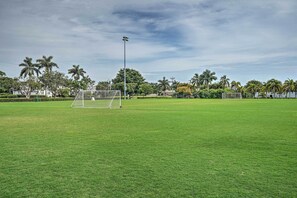 Een voetbalveld met een doelpaleizen, omringd door palmbomen en een heldere lucht.
