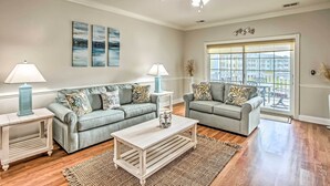 A living room with two grey sofas, a white coffee table, and a ceiling fan. - Magnolia Pointe Condo with Community Pool & More! (Myrtle Beach)