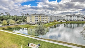 A residential area with a pond, a walking path, and multi-story buildings with balconies. - Magnolia Pointe Condo with Community Pool & More! (Myrtle Beach)