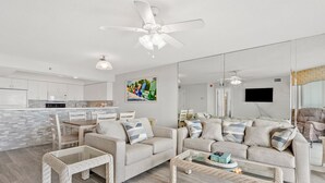 A modern living room with a sofa, coffee table, and wicker chairs. A ceiling fan and pendant light are visible. - Spacious family-friendly oceanfront condos w/easy beach access in North Myrtle Beach (North Myrtle Beach)
