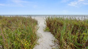 A sandy path leading to a beach with tall grasses on either side. - Spacious family-friendly oceanfront condos w/easy beach access in North Myrtle Beach (North Myrtle Beach)