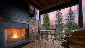 Una terraza de madera con chimenea, asientos al aire libre y una parrilla.