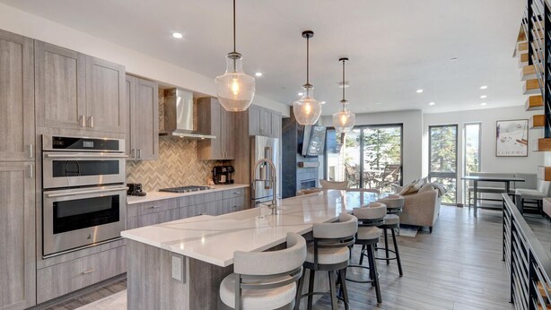 Una cocina moderna con una isla grande, electrodomésticos de acero inoxidable y una zona de bar con taburetes.