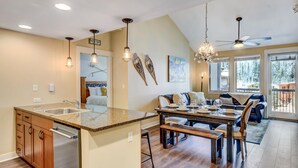 A spacious kitchen with a central island, a dining area with a wooden table, and a ceiling fan.