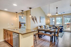 A spacious kitchen with a central island, a dining area with a wooden table, and a ceiling fan.