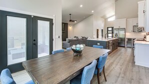 A modern kitchen with a dining area, featuring a wooden table, blue chairs, and a bowl of decorative items. - Lakefront Hot Springs Home w/ Private Dock (Hot Springs)