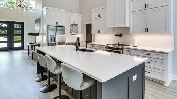 A modern kitchen with white cabinets, a large island with bar stools, stainless steel appliances, and a view of the outdoors. - Lakefront Hot Springs Home w/ Private Dock (Hot Springs)