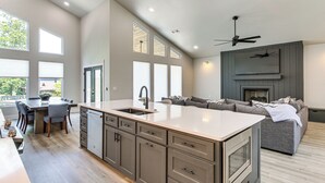 A spacious kitchen with a central island, a dining area with chairs, a sofa, and a fireplace. - Lakefront Hot Springs Home w/ Private Dock (Hot Springs)
