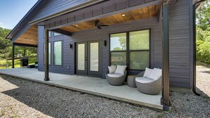 A modern house with a covered porch, large windows, and outdoor seating. - Lakefront Hot Springs Home w/ Private Dock (Hot Springs)