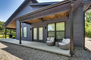 Une maison moderne dotée d’un porche abrité, de grandes fenêtres et d’un espace salon extérieur.