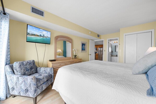 A hotel room with a bed, a chair, a dresser, a TV, a mirror, and a door leading to a kitchenette. - *Fall into Savings-20% Off New Bookings thru 2026* (Murrells Inlet)