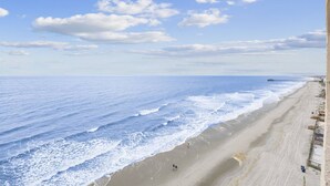 A beach with a long stretch of sand, a pier extending into the water, and a few people walking along the shore. - *Fall into Savings-20% Off New Bookings thru 2026* (Murrells Inlet)