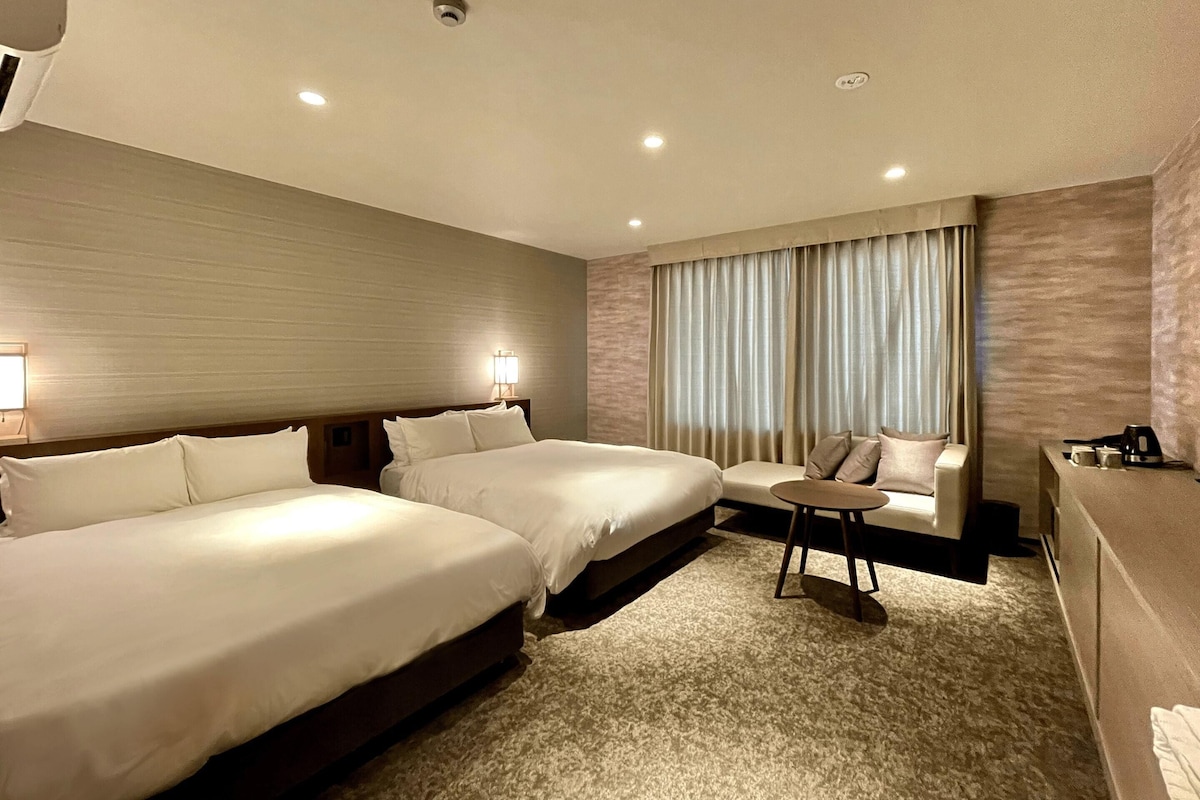 Una habitación de hotel con dos camas, un espacio de descanso pequeño y un escritorio.
