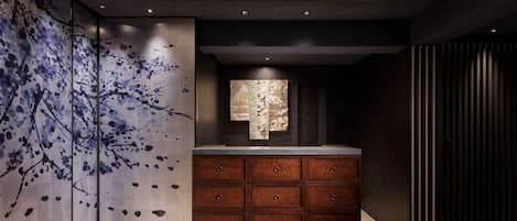 A modern bathroom with a large mirror, wooden cabinets, and a unique wall art design.