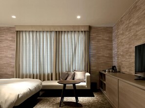 A hotel room with a bed, a sofa, a small table, a TV, and a minibar. - KYOTO GRANBELL HOTEL hanareya (Kyoto)