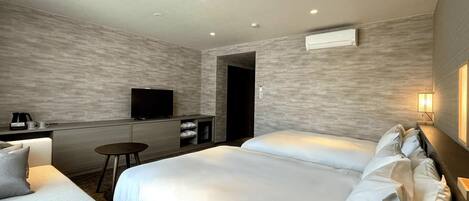 A hotel room with a bed, a sofa, a desk, a television, and a lamp.