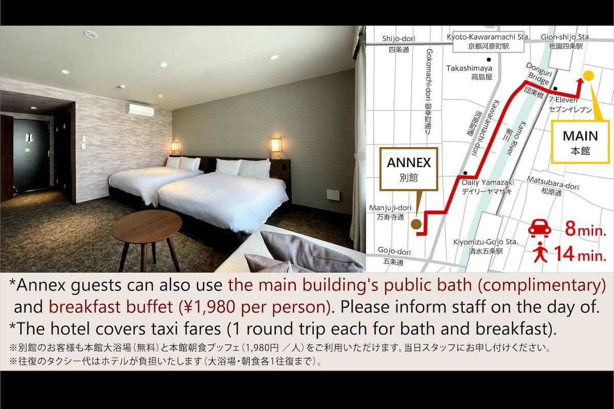 A hotel room with two beds, a small table, and a bathroom.