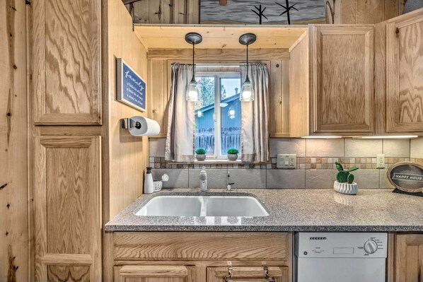Compact kitchen with sink, stainless steel dishwasher, and wooden cabinetry.