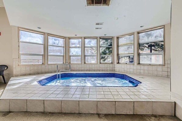 A hot tub in a corner with large windows, a chair, and a tiled floor. - Near Lifts, Ski Keystone, sleeps up to 6ppl (Keystone)