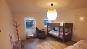 Une petite pièce comprenant un lit superposé, une chaise, un bureau et une fenêtre.