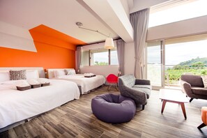 Une chambre d’hôtel moderne avec deux lits, un canapé, un fauteuil rouge et un balcon offrant une vue sur la verdure.