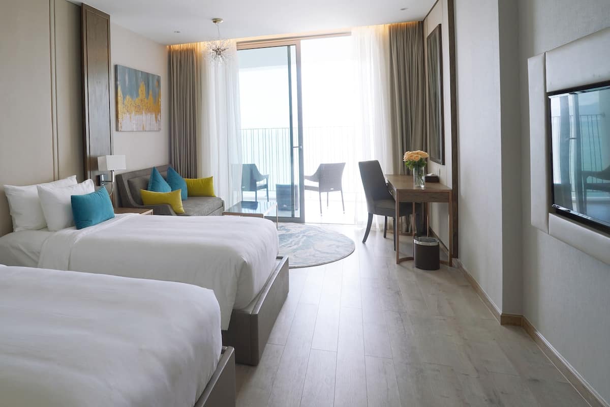 Une chambre d’hôtel avec deux lits, un bureau et un balcon.