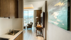 A modern kitchen with a built-in dishwasher, a dining area with a table and chairs, and a large window offering a city view. - Panorama Luxstay Nha Trang (Nha Trang)