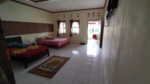 Quarto com duas camas, piso em azulejos e televisão na parede.