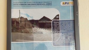 Cartaz informativo emoldurado sobre Borobudur, com texto e fotografia de um edifício tradicional.