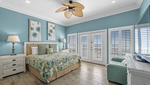 A bedroom with a bed, bedside tables, a ceiling fan, and a window with blinds.