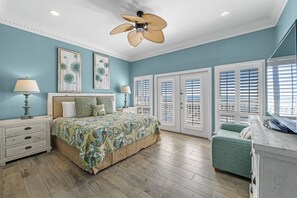 A bedroom with a bed, bedside tables, a ceiling fan, and a window with blinds.