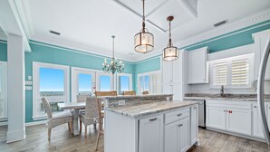 A kitchen with a large island, white cabinetry, and a view to the outside.
