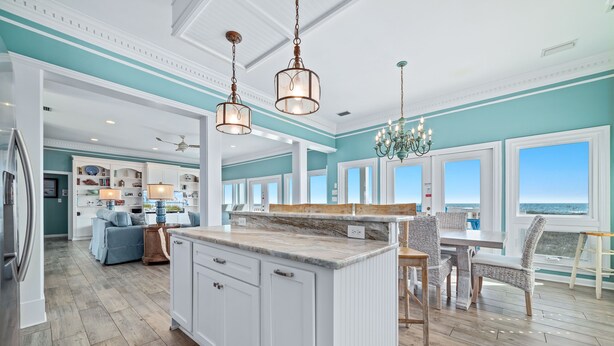 A spacious kitchen with a large island, white cabinetry, and a view to the outside.